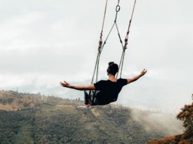 Blake Miner on a large swing with his arms out at his sides as he swings over a large valley