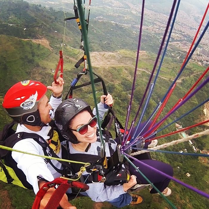 A photo from above shows lolly sitting below a parachute as she flies through the sky in Medellin