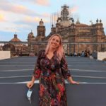 Lolly stands in front of a grand building in Mexico city with scaffolding on the highest part of it