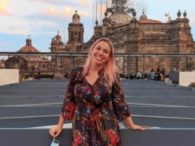 Lolly stands in front of a grand building in Mexico city with scaffolding on the highest part of it