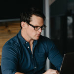 Lauren Ross sits at a desk working on his laptop in front of him