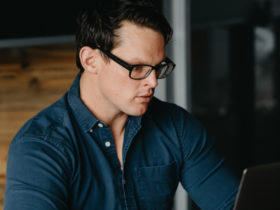 Lauren Ross sits at a desk working on his laptop in front of him