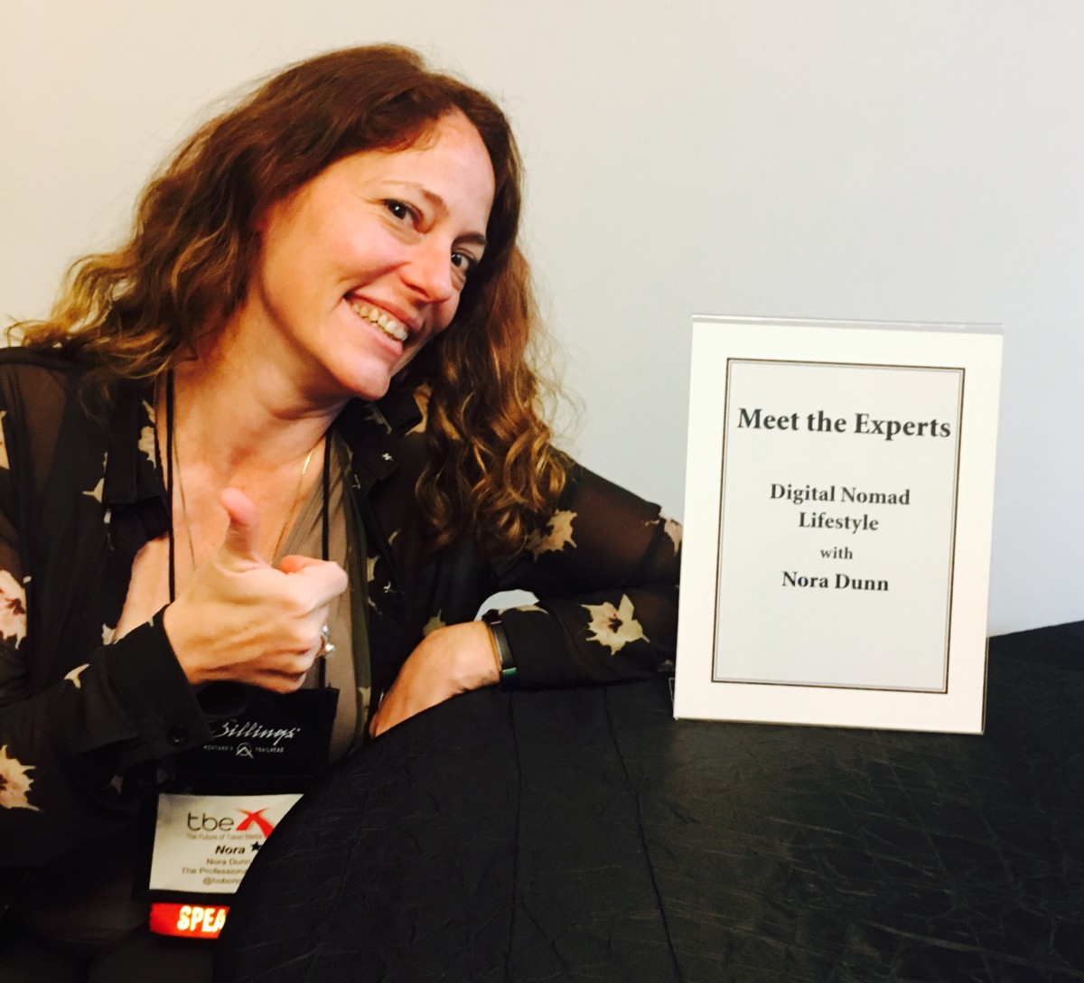 Nora Dunn sits next to a small framed paper that indicates her speech on digital nomading at TBEX