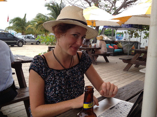 Nora Dunn sits at a table working on her laptop in the Caribbean