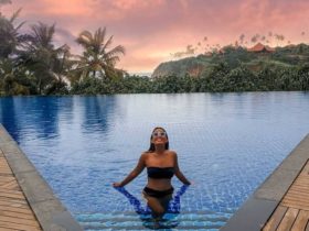 Anna stands at the base of a set of stairs in a pool with her arms by her sides touching the surface of the water