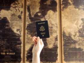 A hand holds up a US passport in front of a world map