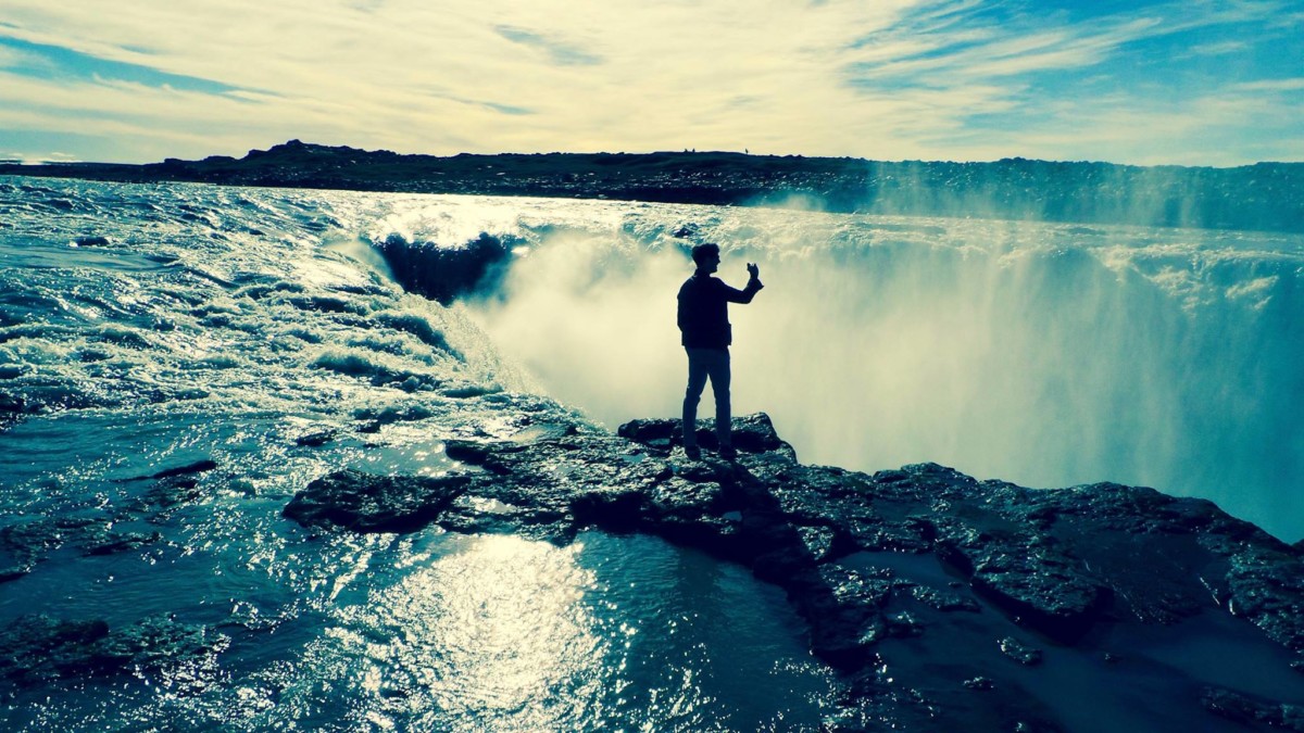 Blake Miner stands on the edge of a semi-circle waterfall in iceland