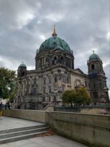 An old building in Berlin with a domed, green roof and a gold pillar