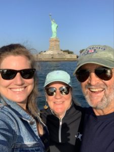 Katherine conaway stands on the left with her mom in the center and her father on the right all wearing sunglasses standing in front of the statue of liberty in NYC