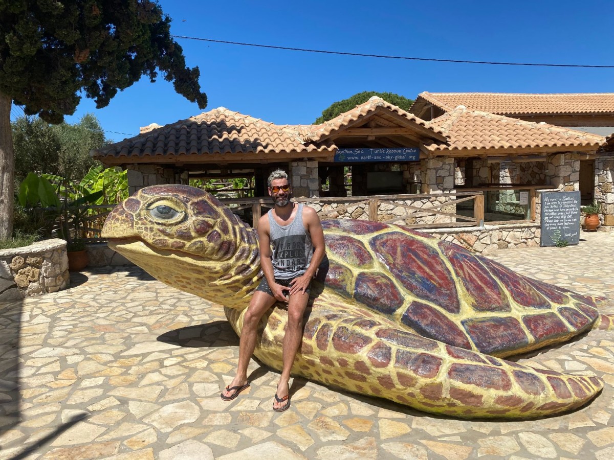 Dirk Bruwer sits on a large sculpture of a turtle that sits in front of a building
