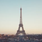 a shot of the eiffel tower from a good distance away shows it with a hazy, multicolored sky