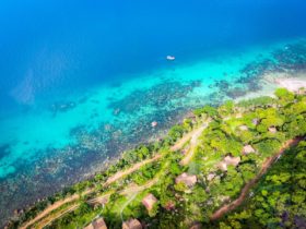 an aerial view of a beach on phu quoc island shows turquoise and blue ocean with lush green vegetation on land