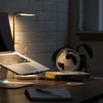 A macbook on a laptop stand on a work desk at night