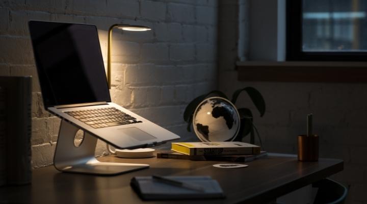 A macbook on a laptop stand on a work desk at night