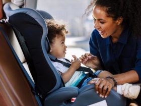 African American woman fastening her child to a denim blue car seat