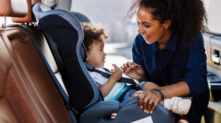African American woman fastening her child to a denim blue car seat