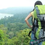 Young female traveler enjoying the view of on top of a hill after a long hike