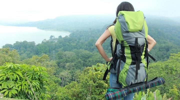 Young female traveler enjoying the view of on top of a hill after a long hike