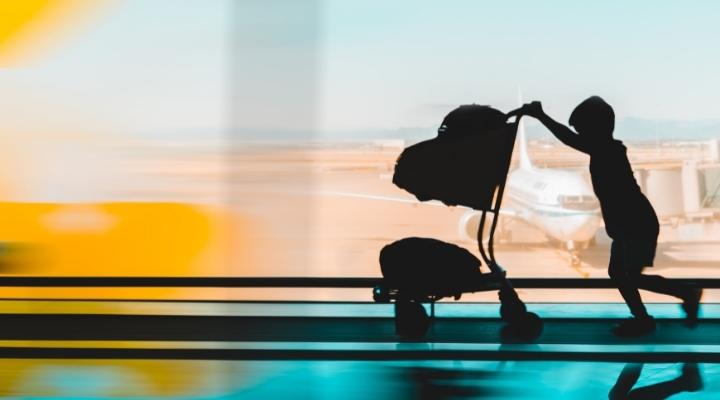 Kid pushing his luggage stroller in the airport