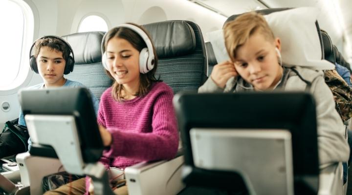 Three kids watching a movie at the airplane