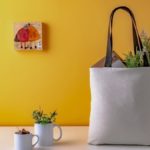 Travel tote bag filled with numerous items on a table