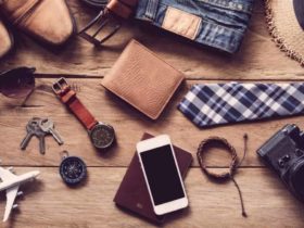 Various travel gifts for men laid on a wooden plank table