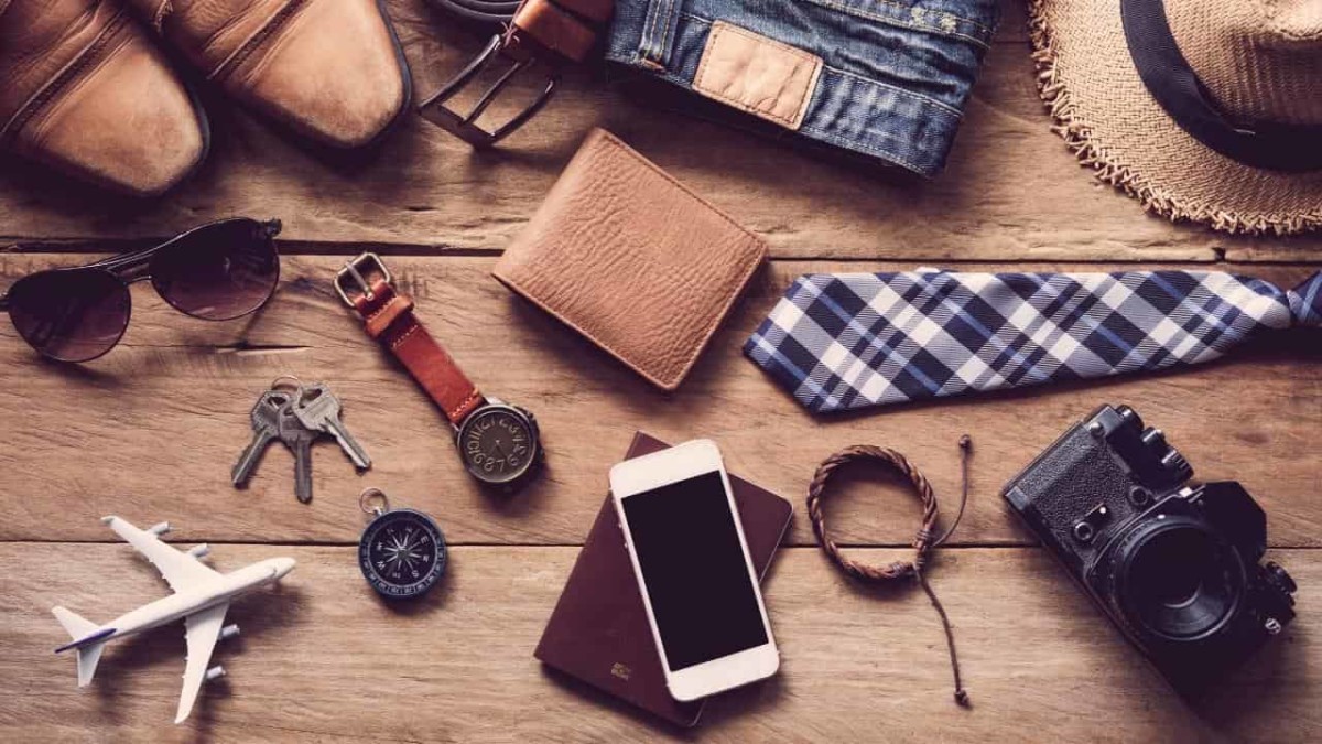 Various travel gifts for men laid on a wooden plank table