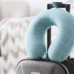Light blue travel pillow on top of a grey suitcase