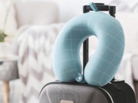 Light blue travel pillow on top of a grey suitcase