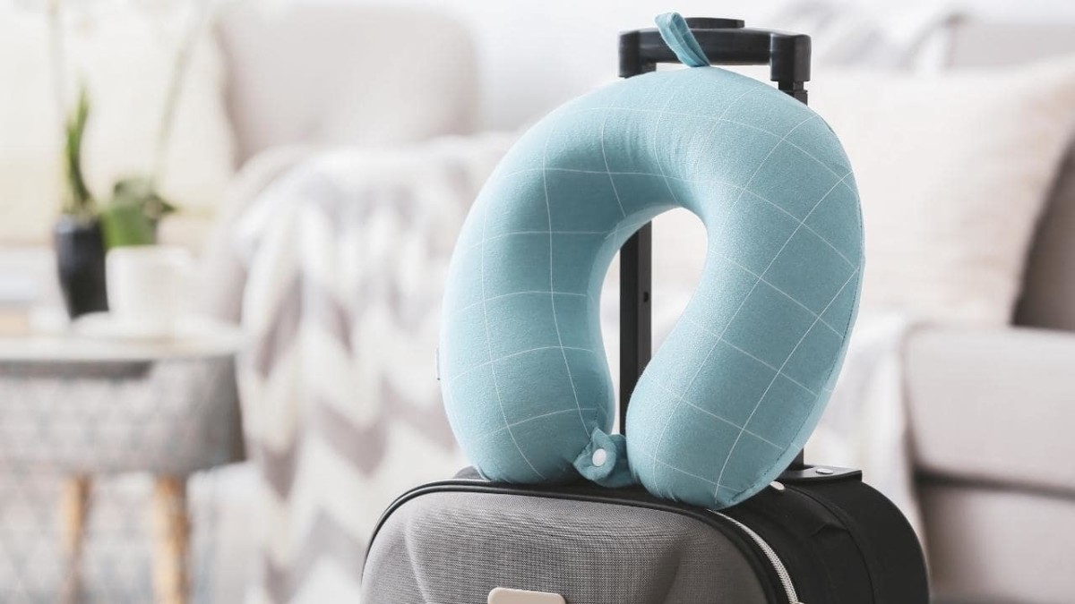 Light blue travel pillow on top of a grey suitcase