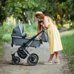 Mother taking her baby to a walk in the park with a travel stroller