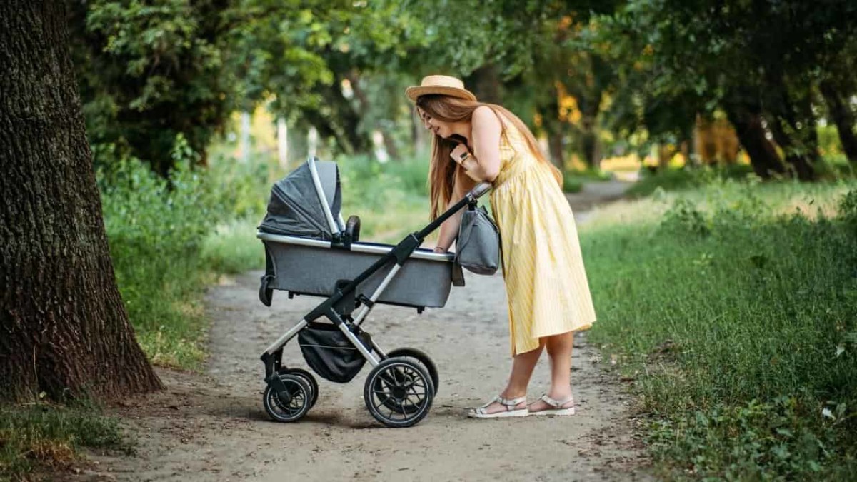 Mother taking her baby to a walk in the park with a travel stroller