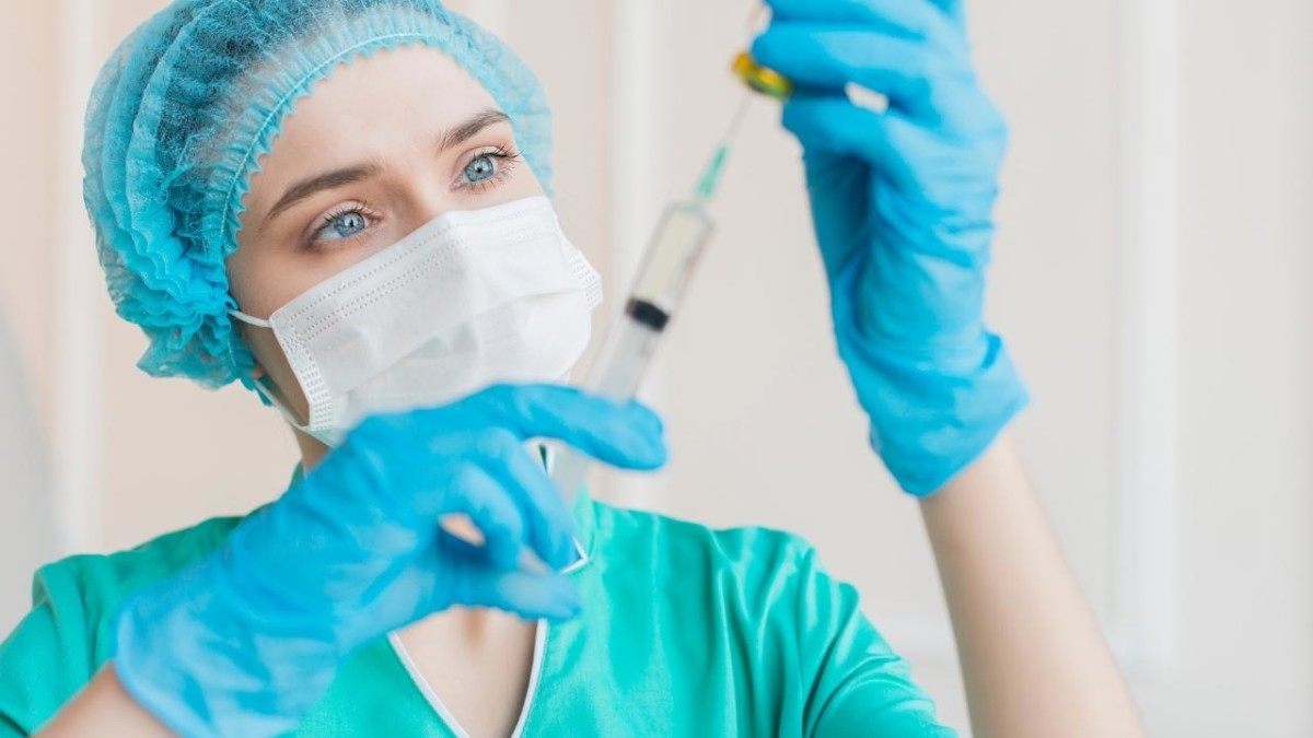 Female nurse squeezing a syringe-full of liquid into a patient's dextrose bag